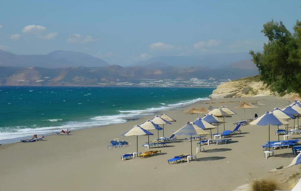 plaża z leżakami i parasolami oraz ocean w obiekcie Almmos w mieście Kalamaki