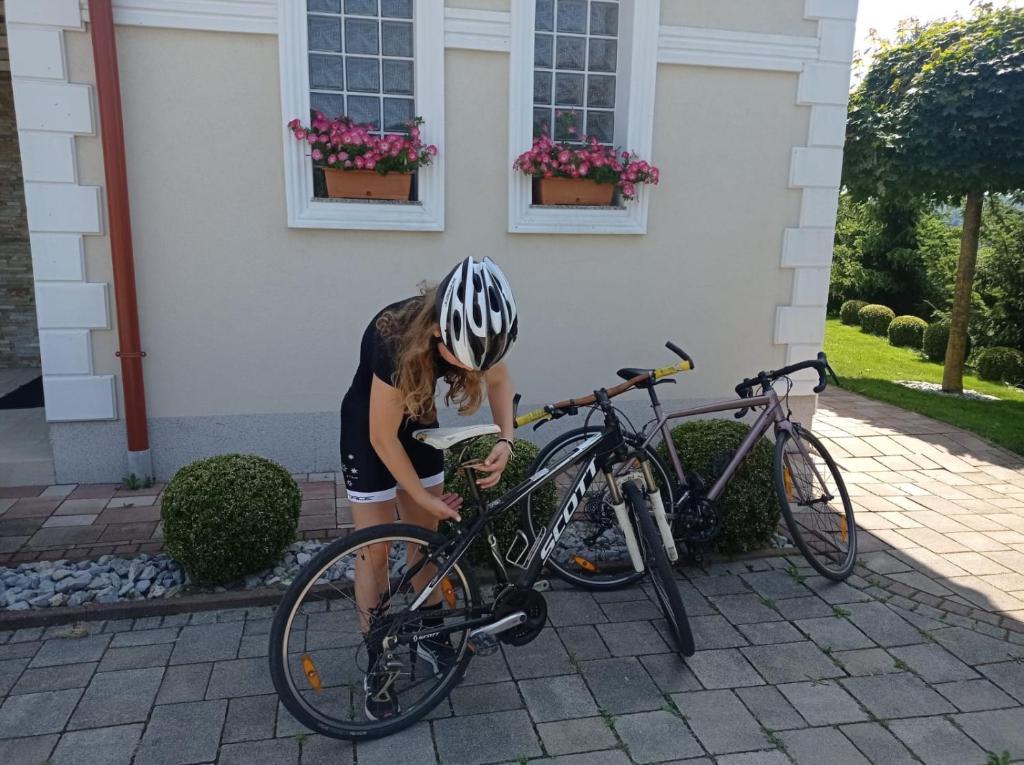 une femme répare un vélo devant une maison dans l'établissement Haloze ForMe, à Zavrč