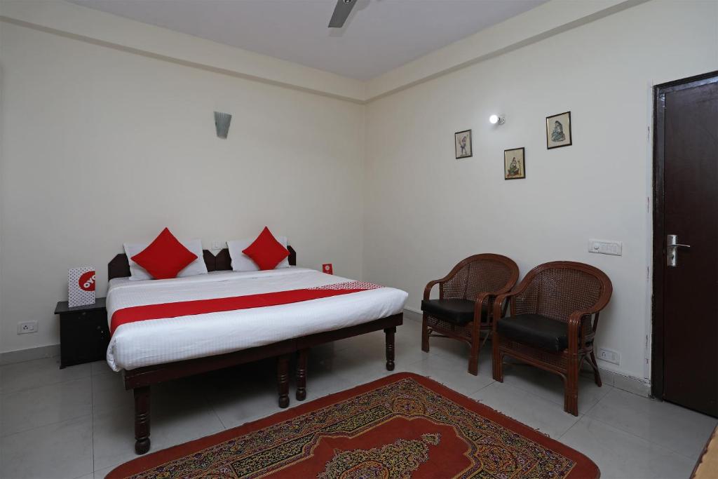 um quarto com uma cama com almofadas vermelhas e 2 cadeiras em OYO Celebration Bnb Home em Ghaziabad
