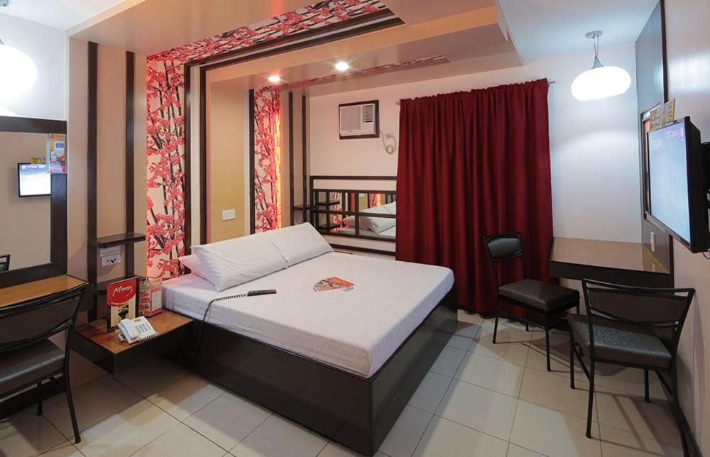 una camera con letto, TV e tenda rossa di Hotel Sogo Cebu a Adlawon