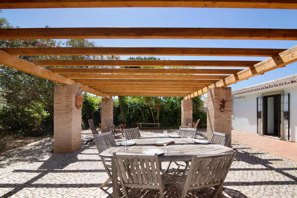 een patio met een tafel en stoelen onder een houten pergola bij Fontenoy in Tavira