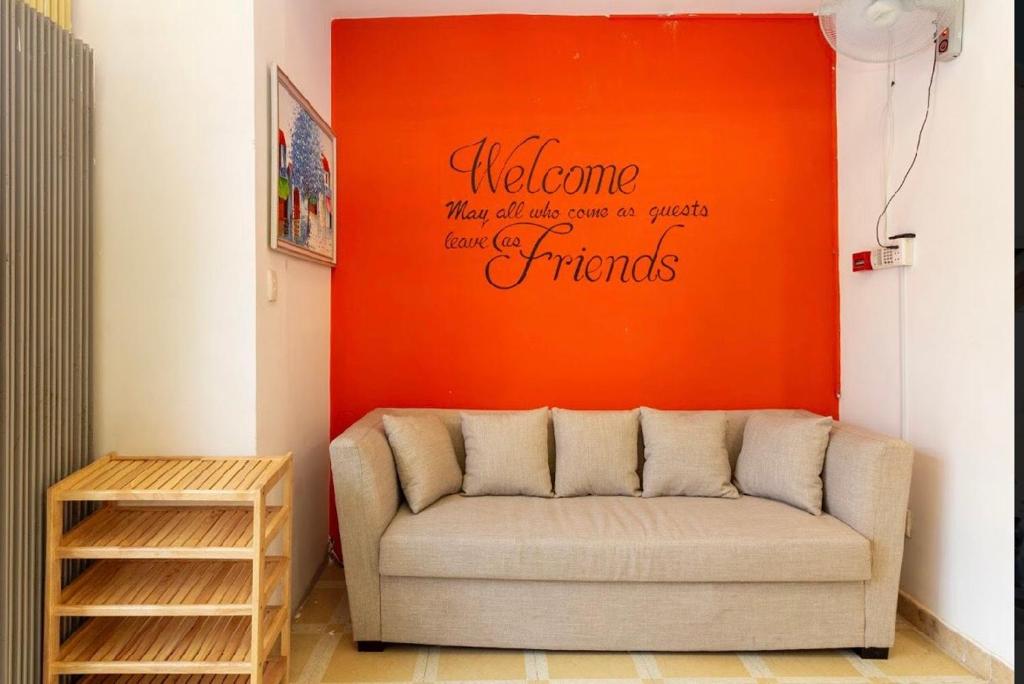 a couch in a room with an orange wall at Ehome Saigon - Gạo hostel in Ho Chi Minh City