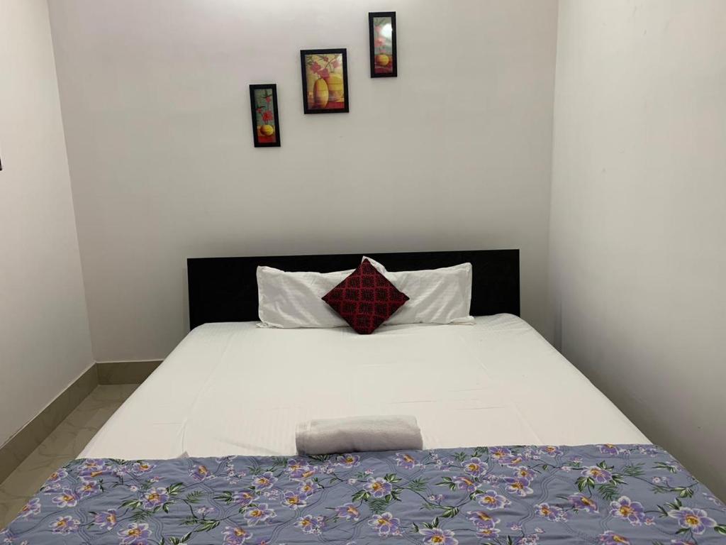 a bedroom with a white bed with three pictures on the wall at JP Hotel in Tezpur