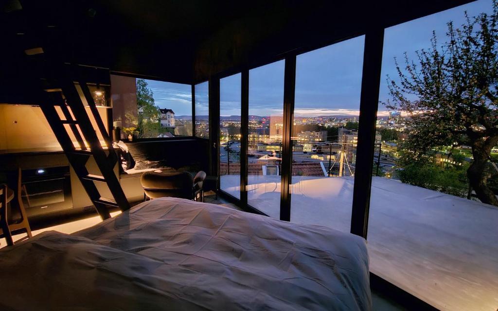 Edge Oslo - Hideaway with Breathtaking City Views في أوسلو: غرفة نوم بسرير ونافذة زجاجية كبيرة
