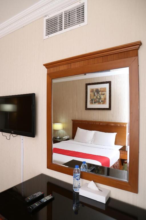 a reflection of a bedroom with a bed in a mirror at City Plaza Hotel in Fujairah
