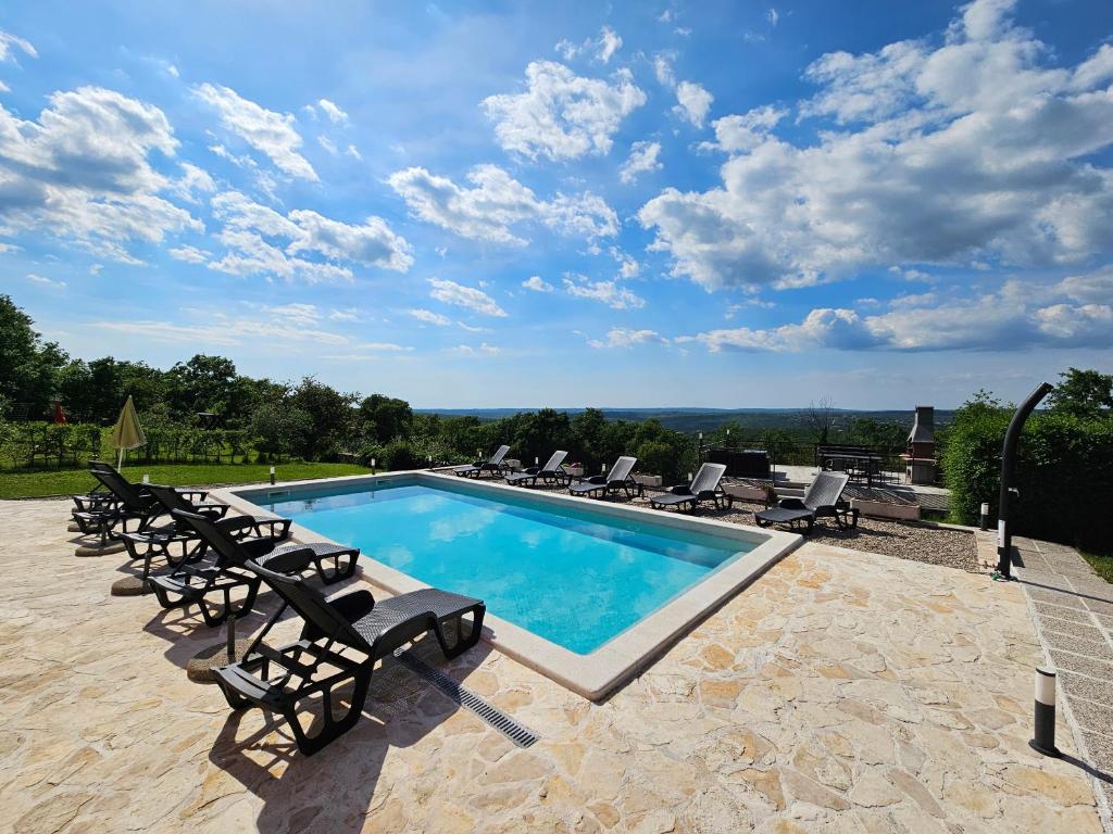 a swimming pool with chaise lounge chairs and a swimming poolvisor at B&B Rogočana in Labin