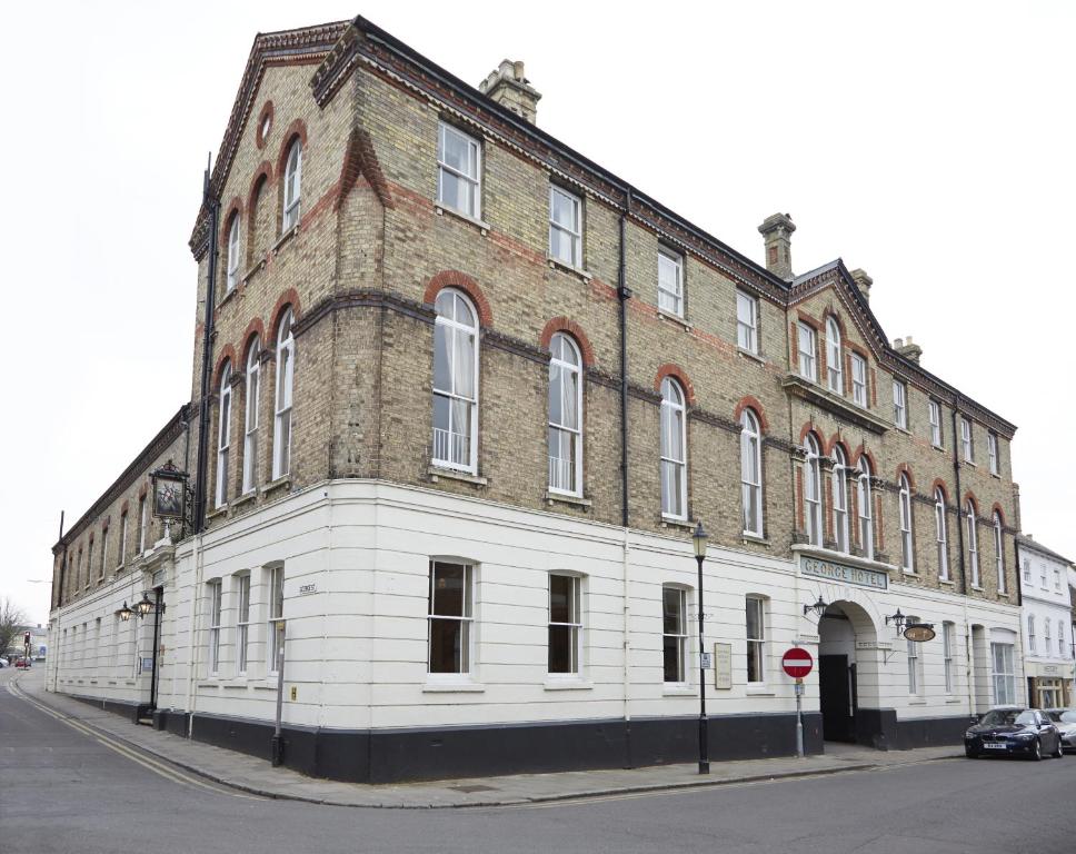 un gran edificio de ladrillo en la esquina de una calle en George Hotel by Greene King Inns, en Huntingdon