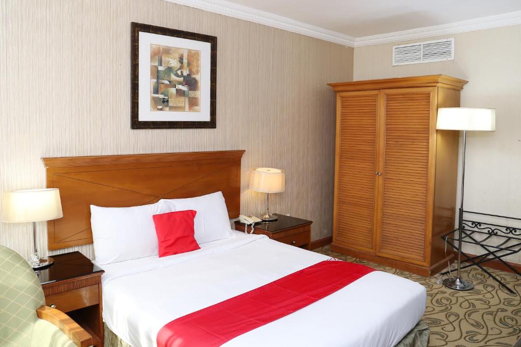 a hotel room with a large bed with a red pillow at City Plaza Hotel in Fujairah