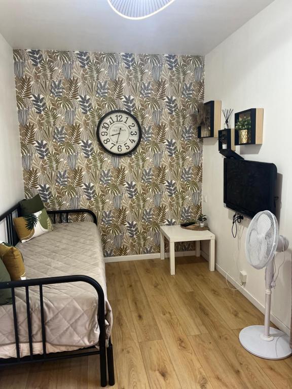 um quarto com uma cama e um relógio na parede em Appartement confortable Olympic games JO24 em Aubervilliers