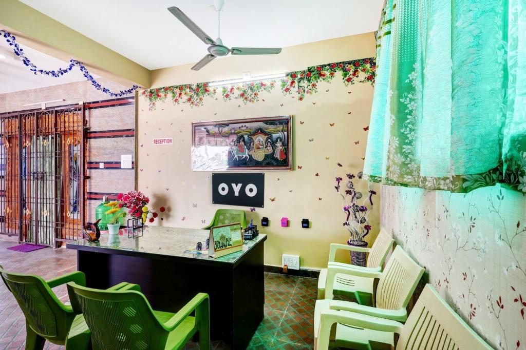 OYO SS Home Stay - An Unique Home Stay في تيروباتي: غرفة بها مكتب وكراسي خضراء