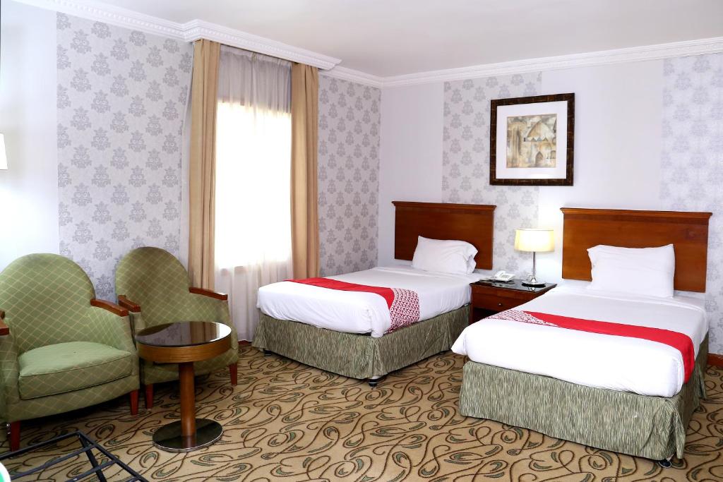 a hotel room with two beds and a chair at City Plaza Hotel in Fujairah