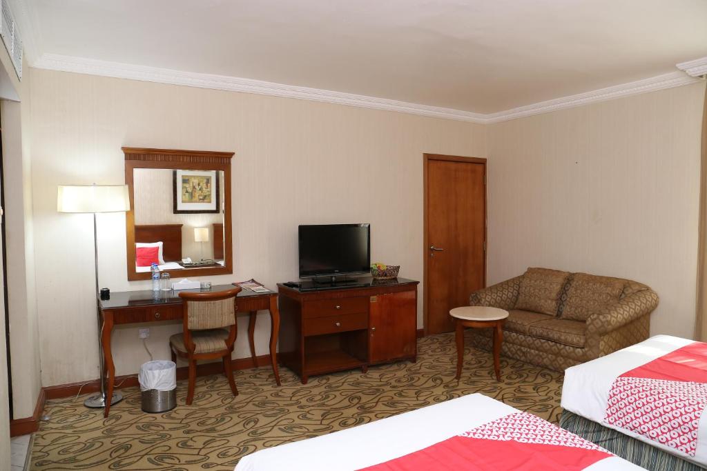 a hotel room with a bed and a desk with a television at City Plaza Hotel in Fujairah