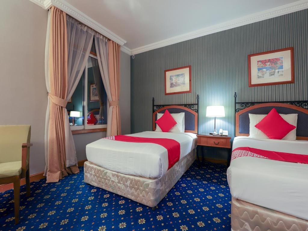 a hotel room with two beds with red pillows at City Plaza Hotel in Fujairah