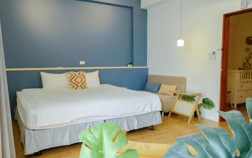 um quarto com uma cama branca e uma parede azul em Cozy Blue B&B em Taitung City
