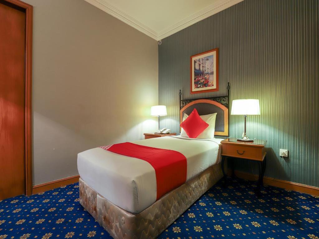 a hotel room with a large bed and two lamps at City Plaza Hotel in Fujairah