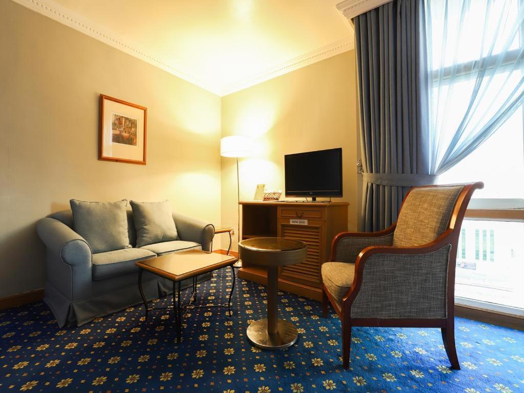 a hotel room with a couch and a tv at City Plaza Hotel in Fujairah