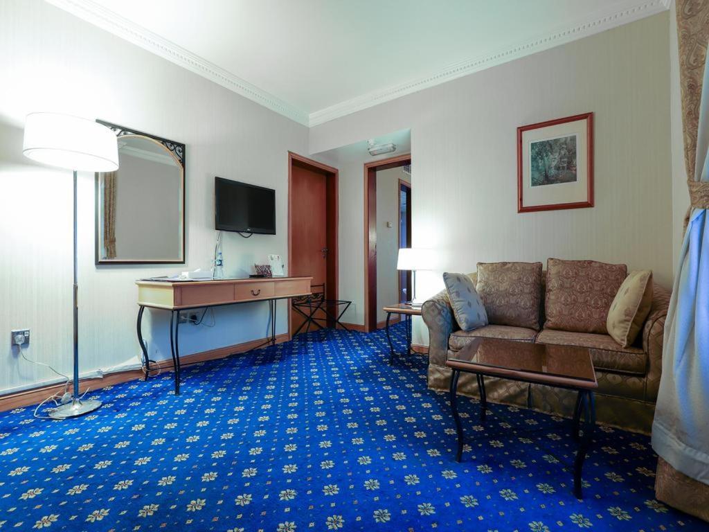 a living room with a couch and a desk in a room at City Plaza Hotel in Fujairah