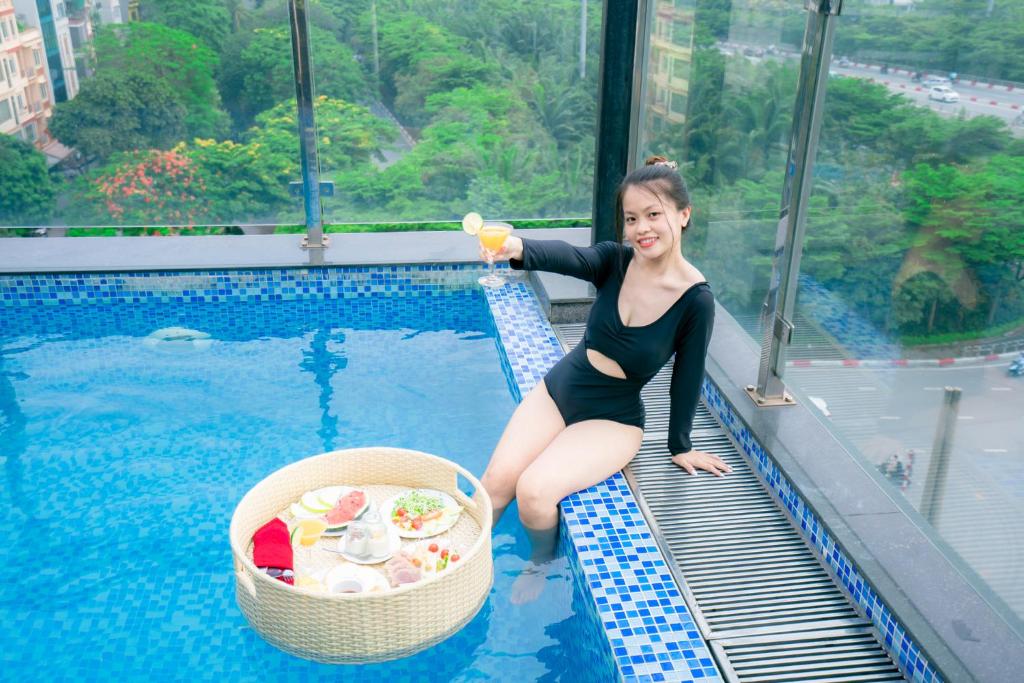 Eine Frau im Badeanzug, die neben einem Pool steht. in der Unterkunft Sunny 22Land Residence Hotel 2 in Hanoi