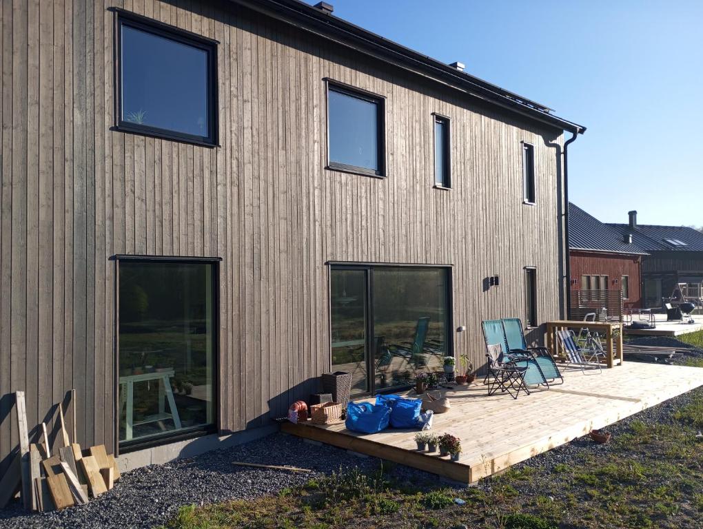 una casa con terraza de madera junto a un edificio en Chill and stay en Ösmo