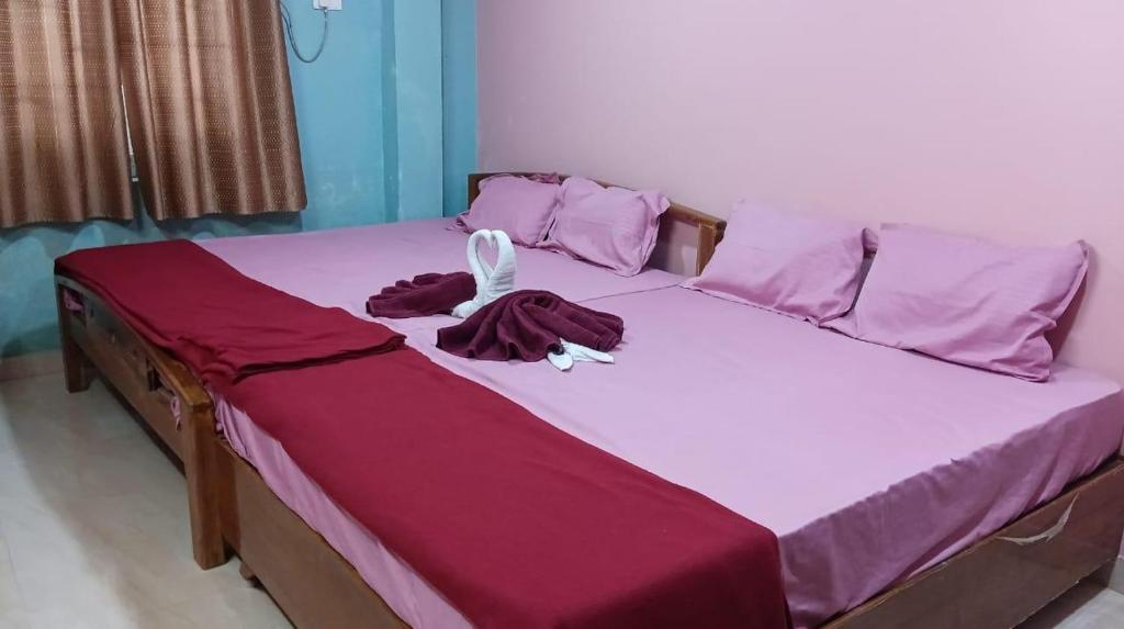 a bed with purple sheets and pink pillows at hotel sudhara in Tirukkadaiyūr