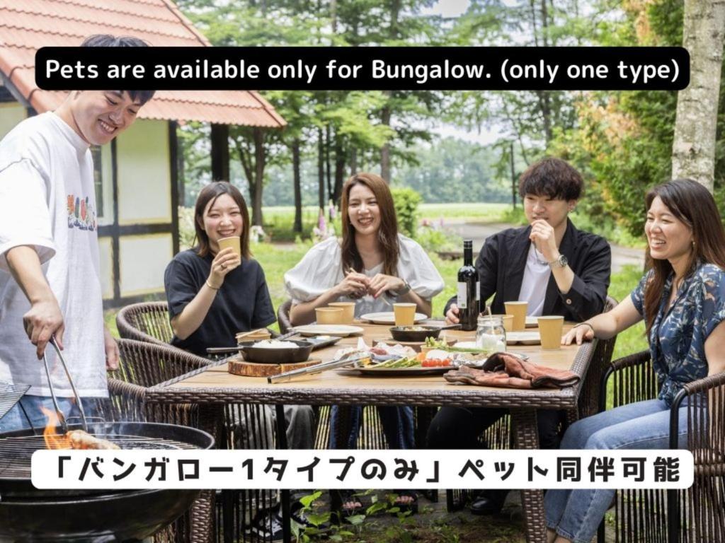 un grupo de personas sentadas alrededor de una mesa comiendo comida en Tokachi Nakasatsunai Glamping Resort Feriendorf en Naka-satsunai