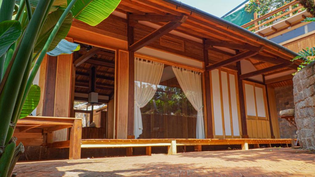 een houten gebouw met een veranda met gordijnen erop bij Harmony Botanical in Buon Ma Thuot