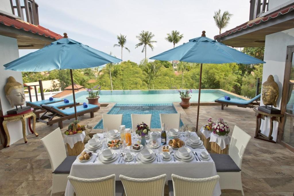 a table with food and drinks on it next to a pool at Royal Majestic Grand Thai Villa in Choeng Mon Beach