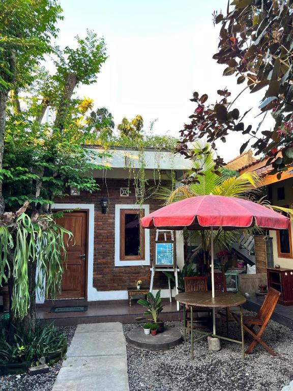 a small house with a table and a red umbrella at Rumah Pathuk Syariah Homestay in Yogyakarta