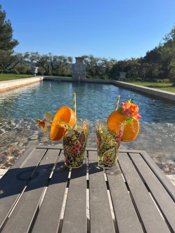tres jarrones con flores en ellos sentados en una mesa cerca de una piscina en L'AMANDERAIE PISCINE PRIVEE à côté de LOURMARIN LUBERON, en Cadenet