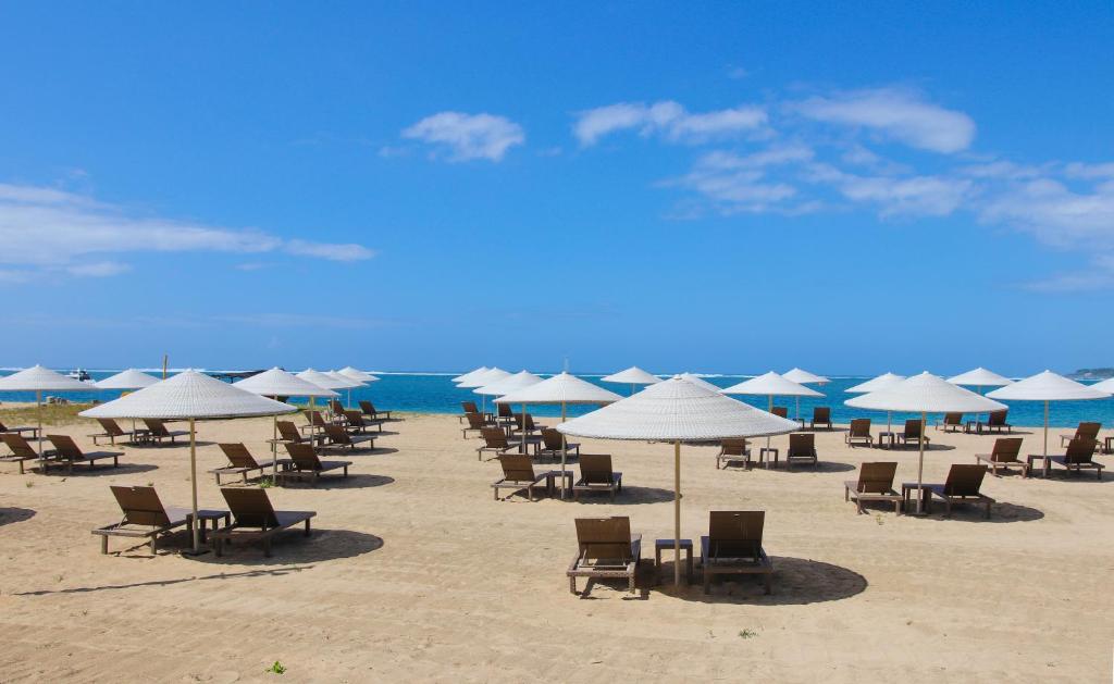 un mucchio di sedie e ombrelloni su una spiaggia di Mercure Resort Sanur a Sanur