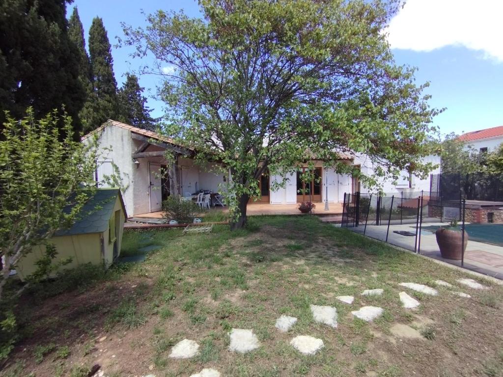 ein kleines weißes Haus mit einem Baum im Hof in der Unterkunft Maison de vacances avec piscine et jardin in Bompas