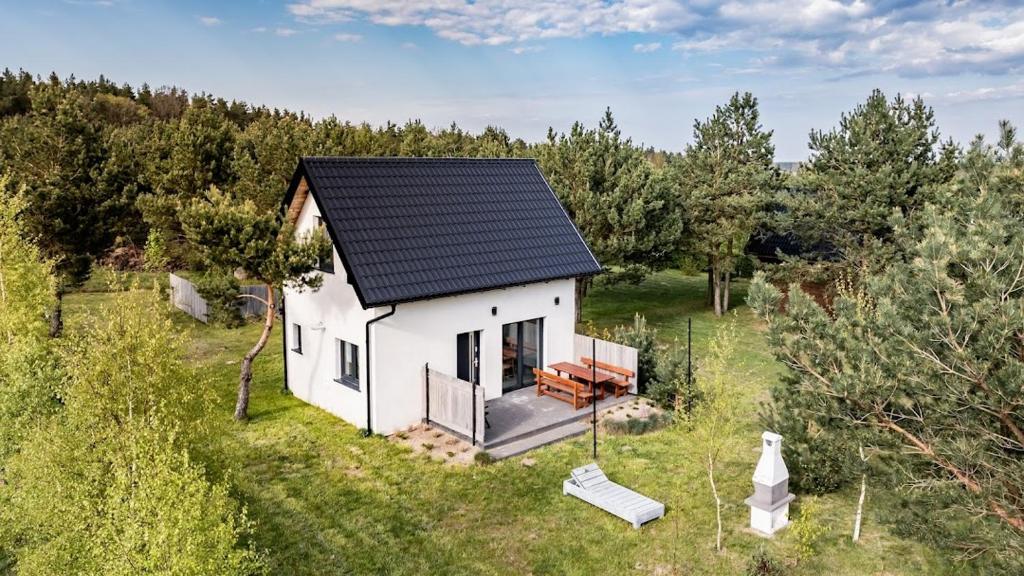 a small white house with a black roof in a field at Domki Lawerka in Wierzchucino