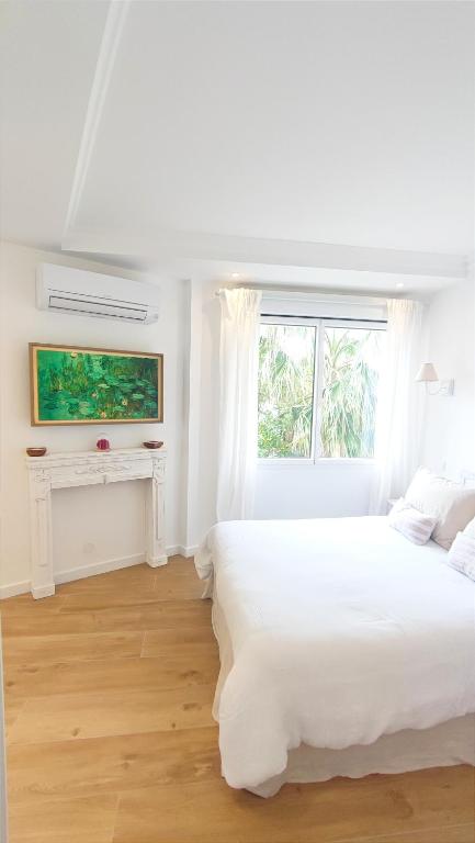une chambre blanche avec un grand lit et une fenêtre dans l'établissement La Dolce Vita de Cannes: Luxury city center apartement, beautiful View, à Cannes