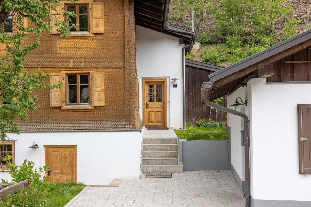 Casa blanca con puerta de madera y escaleras en Haus Victoria, en Schruns