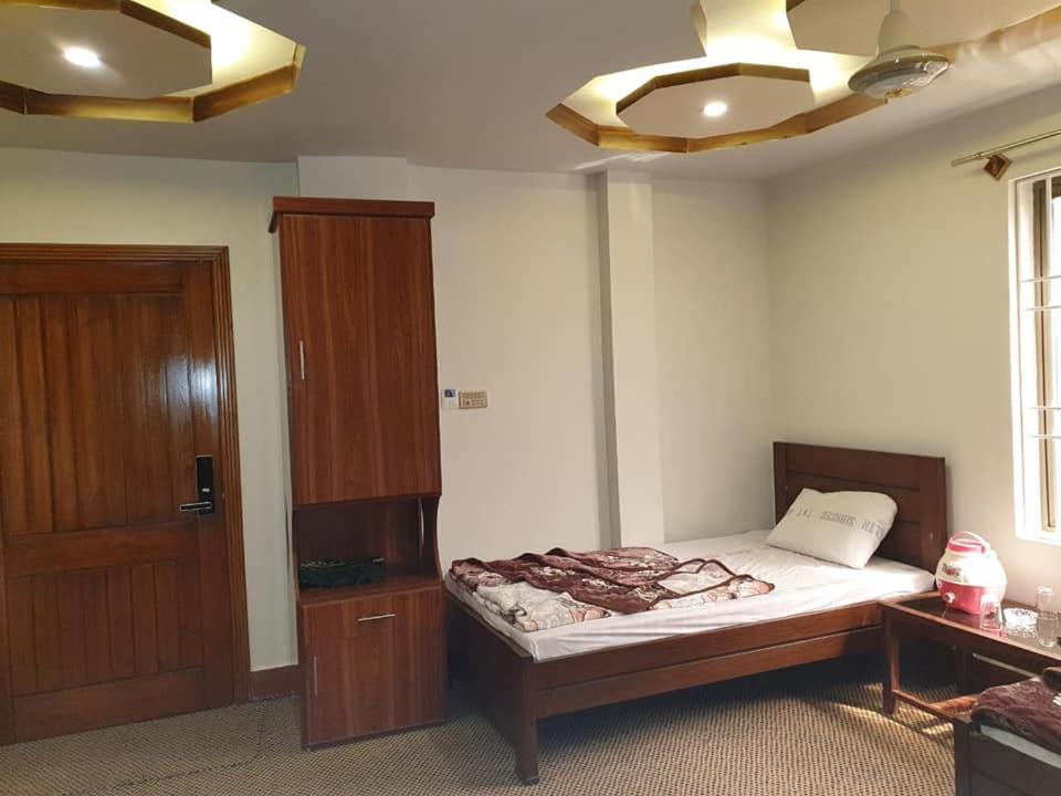 Schlafzimmer mit einem Bett und einem Holzschrank in der Unterkunft Rehan Hotel in Quetta