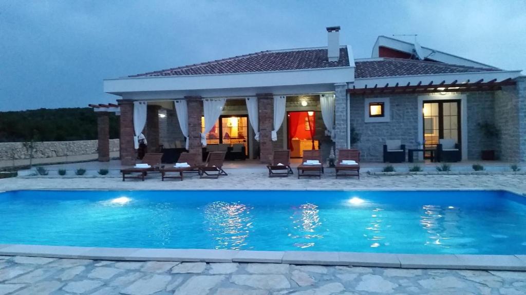 una villa con piscina di fronte a una casa di Villa Melody Novalja a Novalja (Novaglia)