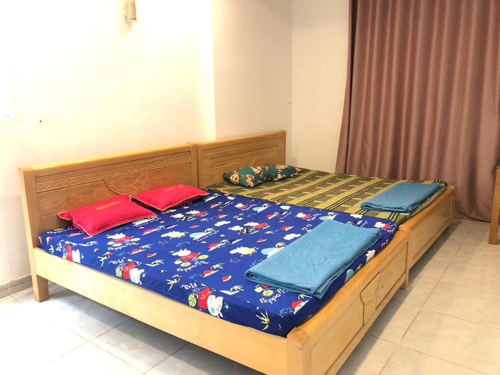 a bed with a blue comforter and red pillows on it at Nhà Nghỉ Minh Thảo in Chơn Thành