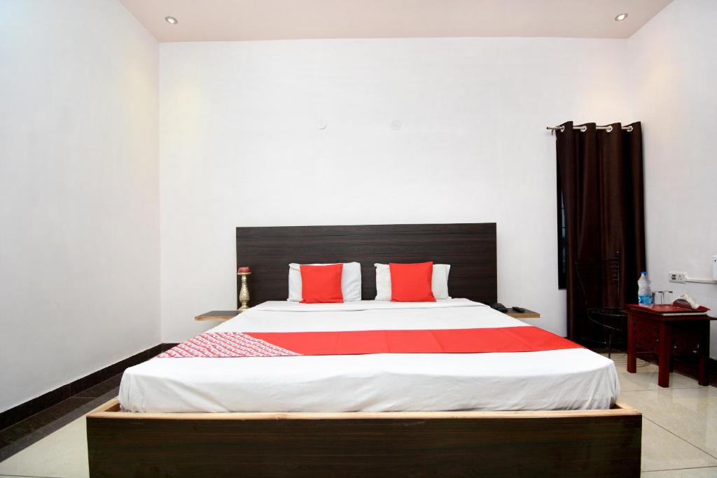 a bedroom with a large bed with red pillows at OYO Flagship 31031 DS Royal Guest House in Ludhiana