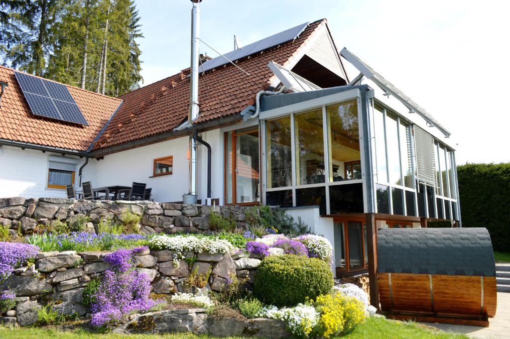 Oberbränd的住宿－Fewo "Alpenliebe" im Haus Fritz, 3 Schlafzimmer, E-Auto-Ladestation, Eisenbach, Titisee，一座石墙、窗户和鲜花的房子