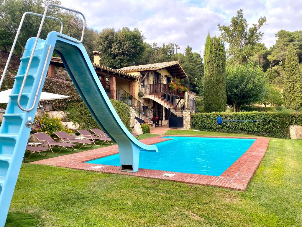 a blue slide in front of a swimming pool at Casa Rural Can Mananna Lloguer íntegre in Sant Feliu de Buixalleu