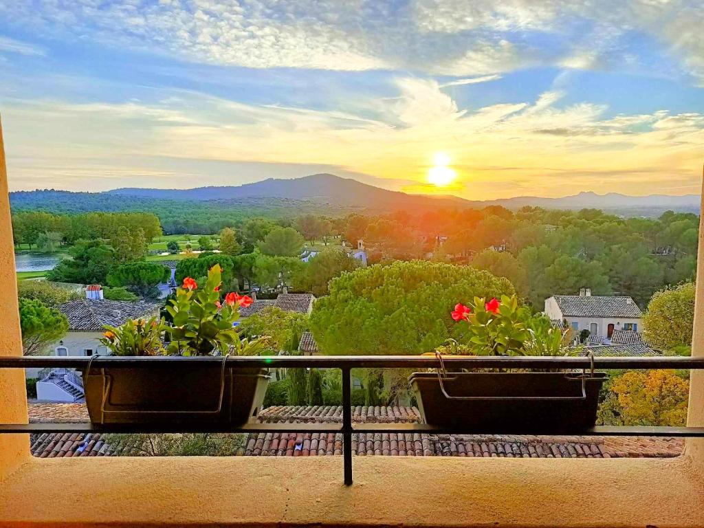 zwei Pflanzen auf einem Balkon mit Blick auf den Sonnenuntergang im Hintergrund in der Unterkunft Charmant T2 climatisé avec belle vue , Golf de Pont-Royal in Mallemort