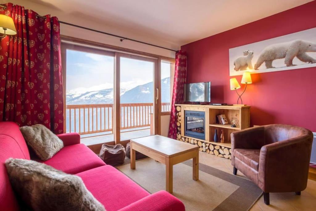- un salon avec un canapé rose et une grande fenêtre dans l'établissement Appartement Luxe Avec Vue : Au Pied des Pistes, à Sainte-Foy-Tarentaise