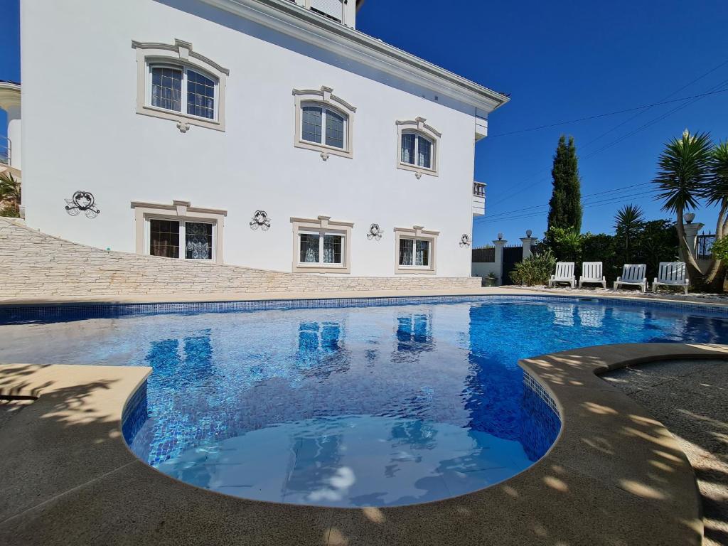 a large swimming pool in front of a white house at Silver Village Residence in Maceira