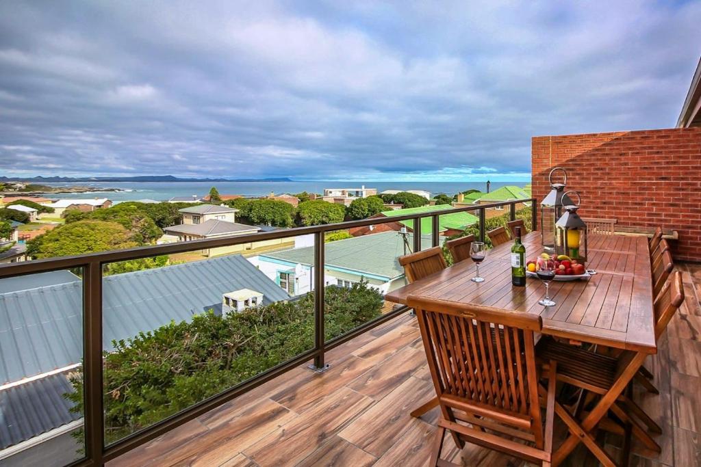 a balcony with a wooden table with wine glasses on it at White Shark Guest House in Gansbaai