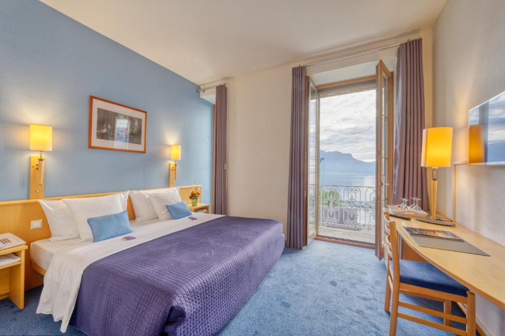 una camera d'albergo con un letto, una scrivania e una finestra di Hôtel Bon Rivage a Vevey