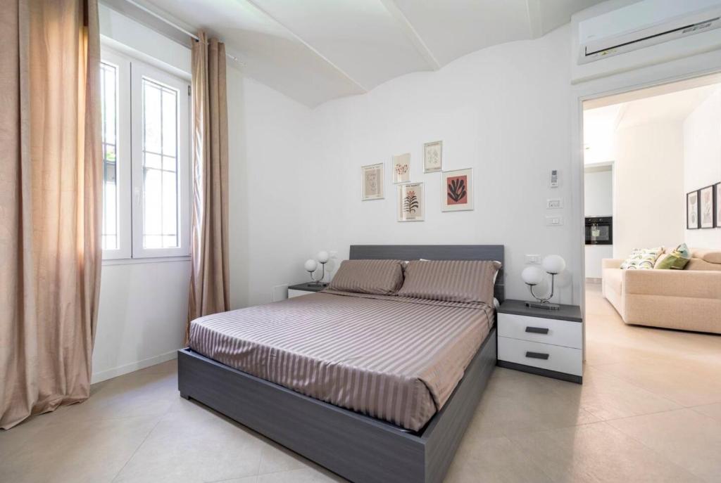 een witte slaapkamer met een bed en een bank bij MONO Apartments Aldini in Bologna