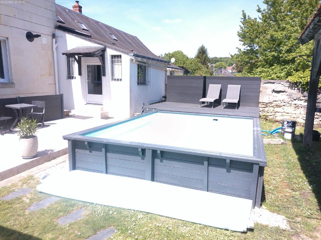 una piscina en un patio trasero con 2 sillas en A 2 pas d AZAY, en Neuil