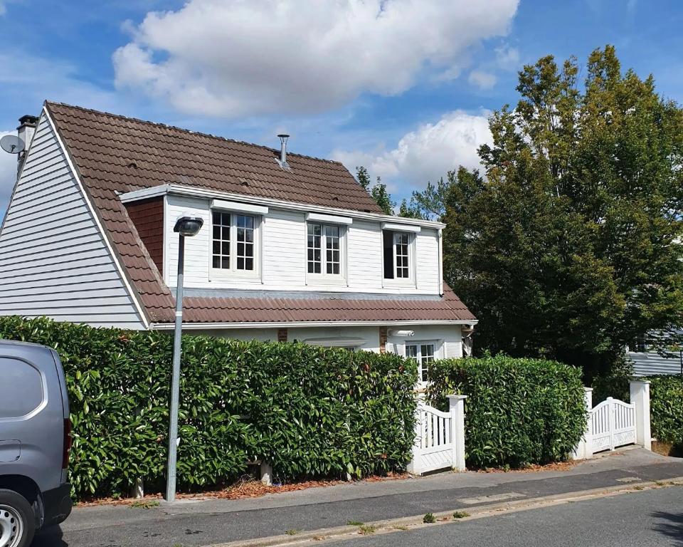 een wit huis met een hek en een auto voor de deur bij Maison de 5 chambres avec jardin clos et wifi a Dammartin en Goele in Dammartin-en-Goële