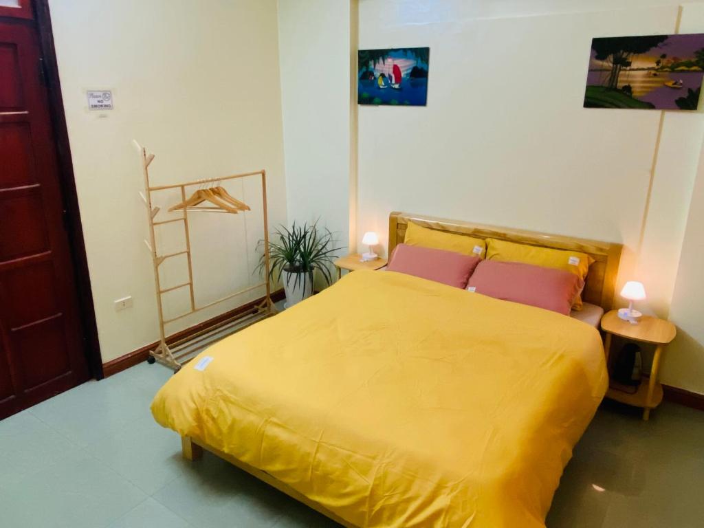 Su Homestay في كاو بانغ: غرفة نوم بسرير اصفر مع وسادتين ورديتين