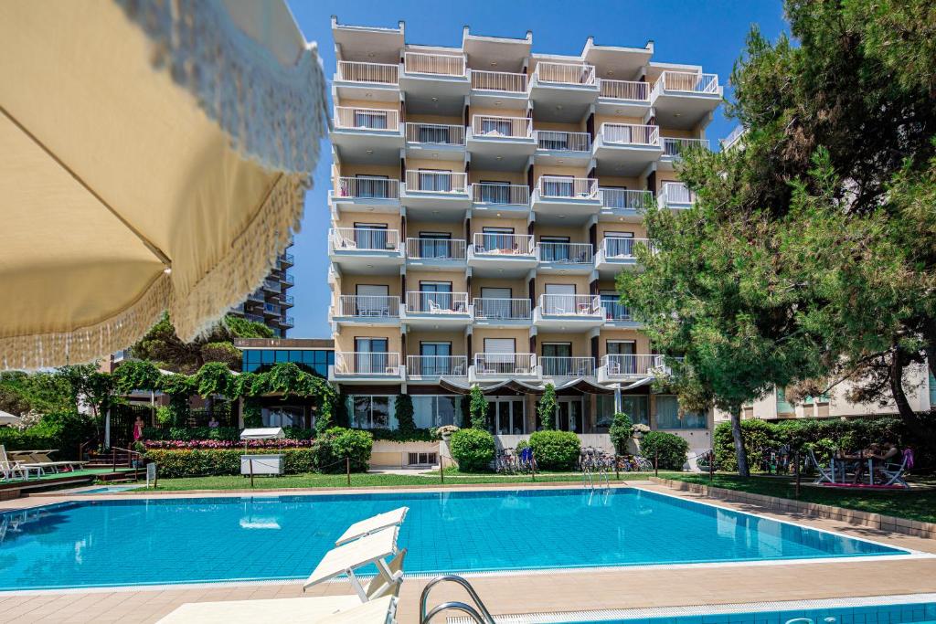 um hotel com piscina em frente a um edifício em Hotel Atlantic em Lignano Sabbiadoro